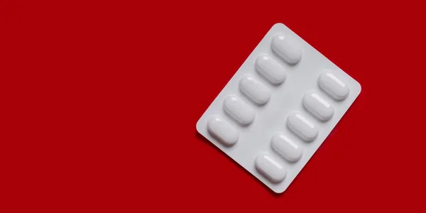 Zbliżenie Nieotwarte Tabletek Białym Tle Czerwonym Tle — Zdjęcie stockowe