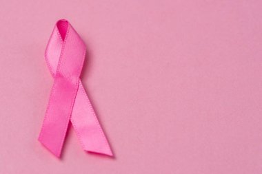 Pembe kurdele göğüs kanseri farkındalığı sembolü pembe arka planda. Kopyalama alanı olan yatay resim.