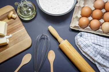 Mutfak gereçleri ve kek pişirme için malzemeler. Yumurta, un ve yağ koyu arka plan üzerinde. Fırın kavramı, yüksek açıdan görünümü.