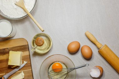 Kek pişirme için malzemeler. Yumurta, un, tereyağı, petrol ve açık renkli tatlım. Metin alanı, üstten görünüm.