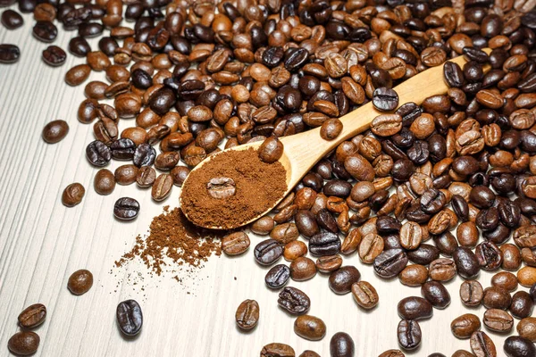 Coffee beans and ground coffee in wooden spoon
