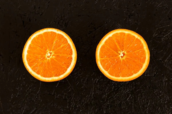 Два ломтика апельсина на черном фоне — стоковое фото
