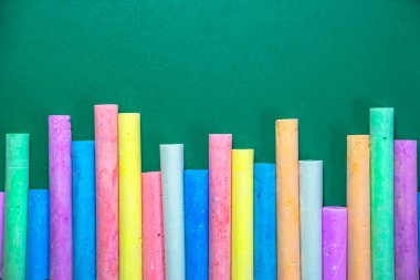 Yeşil bir tebeşir tahtası üzerinde çok renkli tebeşirler