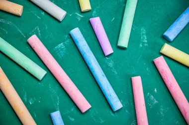 Yeşil bir tebeşir tahtası üzerinde çok renkli tebeşirler