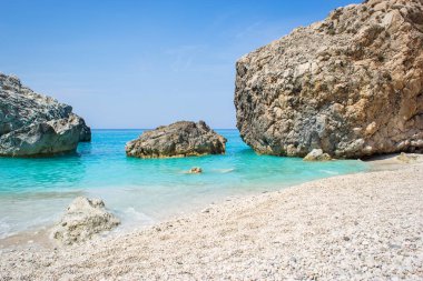 Turkuaz suyu ve büyük kayaları olan güzel kumlu bir sahil.
