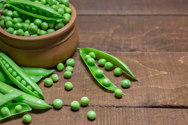 Groene erwten op houten ondergrond — Stockfoto