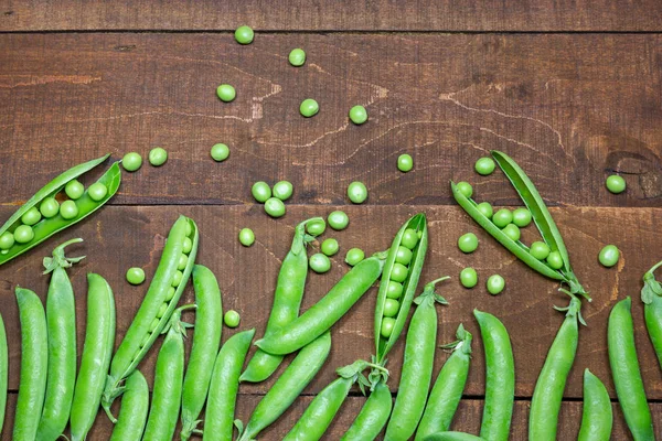 Groene erwten op houten ondergrond — Stockfoto