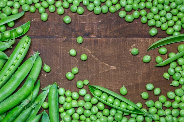 Groene erwten op houten ondergrond — Stockfoto