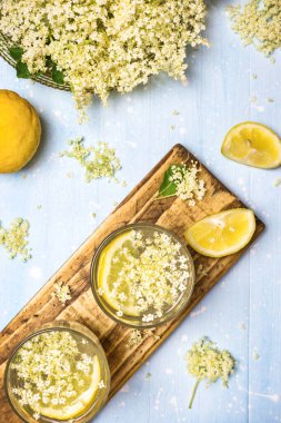 İki bardak ev yapımı mürver çiçeği limonatası ve sağlıklı ve ferahlatıcı içecekler için taze malzemeler..