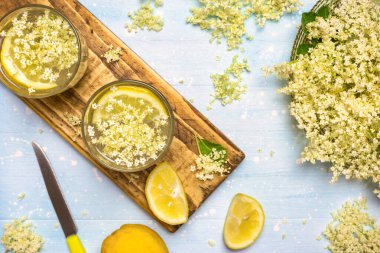 İki bardak ev yapımı mürver çiçeği limonatası ve sağlıklı ve ferahlatıcı içecekler için taze malzemeler..