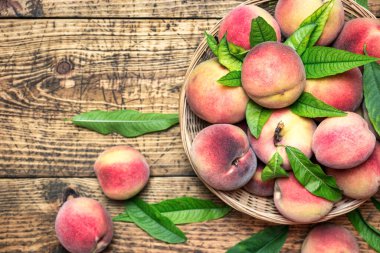 Kırsal ahşap bir masada sepetin içinde taze şeftaliler, üst manzara. Sağlıklı organik meyve.