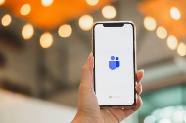 BANGKOK THAILAND - 17 Mayıs 2020: Bir kullanıcının IphoneX 'i tutan ve aygıt ekranında Microsoft Ekip Logosunu gösteren resmini kapat. 