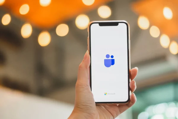 BANGKOK THAILAND - 17 Mayıs 2020: Bir kullanıcının IphoneX 'i tutan ve aygıt ekranında Microsoft Ekip Logosunu gösteren resmini kapat. 