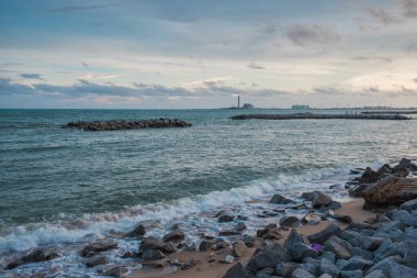 Armourstone duvarı ve dalgalar kıyıda endüstriyel malikanenin arkasında.