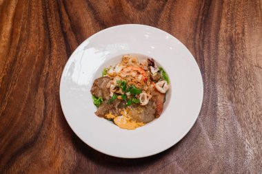 Kızarmış erişteli tavuk ve deniz ürünleri mi yoksa ahşap masada tavuk ve deniz ürünleriyle karıştırılmış kızarmış şehriye mi?.