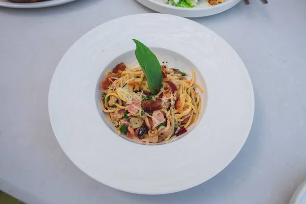 Bacon Chili ya da Spagetti Pad Prik Pastırmalı Spagetti 'nin üst görüntüsü, Tayland usulü İtalyan eritme yemekleri ahşap masada beyaz tabakla servis ediliyor. Beyaz Arkaplan. 