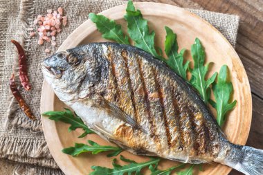 Plaka üzerinde taze roka ile ızgara yaldızlı kafalı çipura