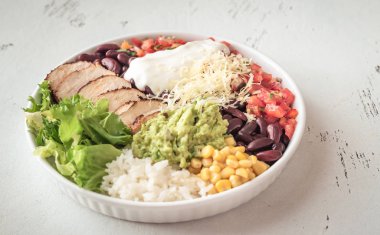 Burrito bowl with chicken, salsa, corn, rice, kidney beans and guacamole clipart