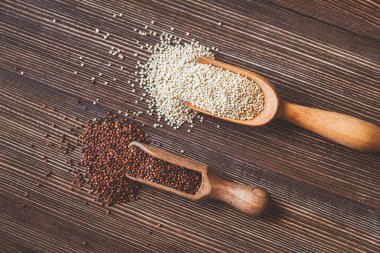 Ahşap arka planda çiğ beyaz ve kırmızı kinoa kalıntıları.