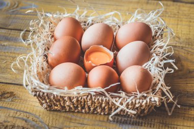 Tahta arka planda bir sepet çiğ tavuk yumurtası.