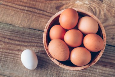 Ahşap zeminde bir kase çiğ tavuk yumurtası.