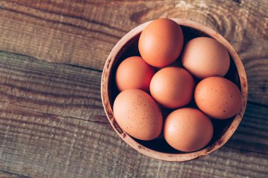 Ahşap zeminde bir kase çiğ tavuk yumurtası.