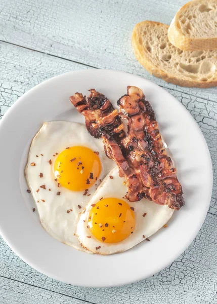 Uova fritte e pancetta sul piatto bianco — Foto Stock