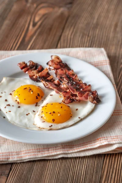 Uova fritte e pancetta sul piatto bianco — Foto Stock