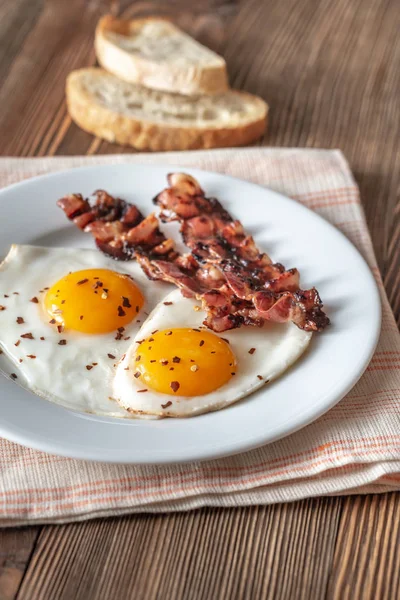 Uova fritte e pancetta sul piatto bianco — Foto Stock