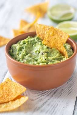 Bowl of guacamole with tortilla chips clipart