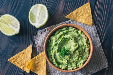Bowl of guacamole with tortilla chips clipart