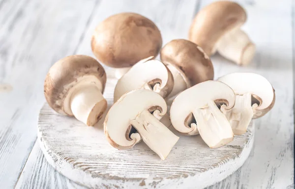 Cogumelos Champignon no tabuleiro de madeira — Fotografia de Stock