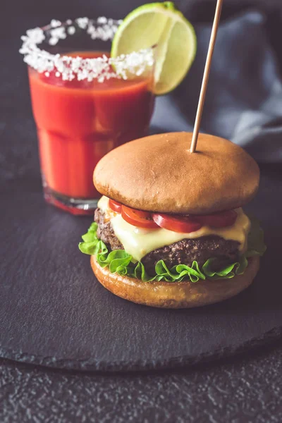 Hamburger mit einem Glas Tomatensaft — Stockfoto