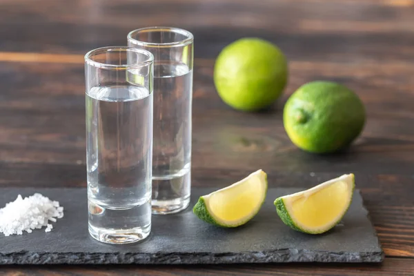 Glas tequila med lime kilar — Stockfoto