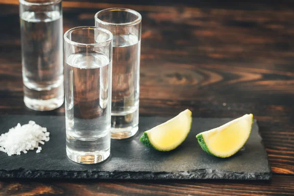 Glasses of tequila with lime wedges — Stock Photo, Image