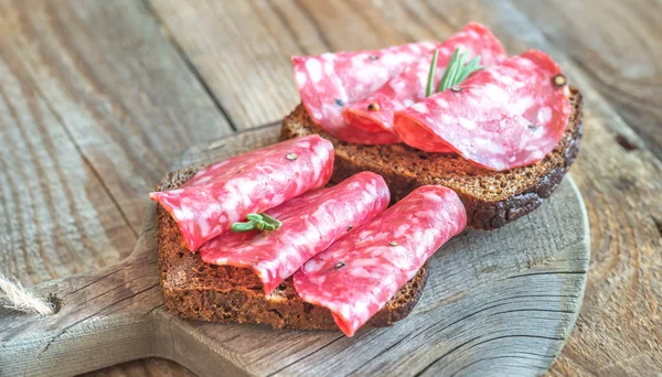 Sandwiches with salami on the wooden board — Stock Photo, Image