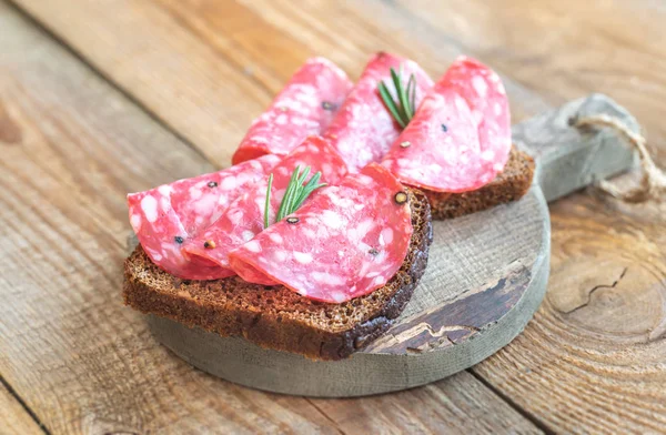 Sandwiches with salami on the wooden board — Stock Photo, Image