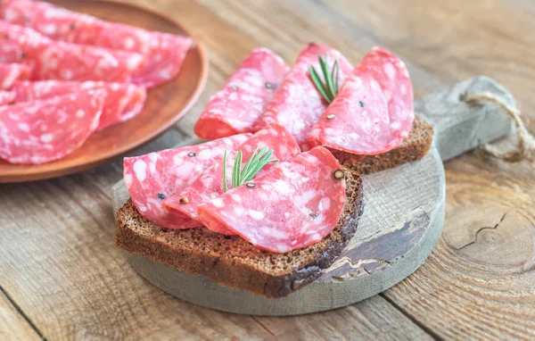 Sandwiches with salami on the wooden board — Stock Photo, Image