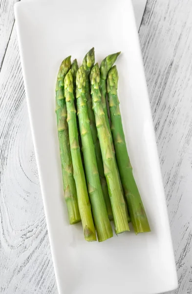 Beyaz servis tabağında kaynamış kuşkonmaz.