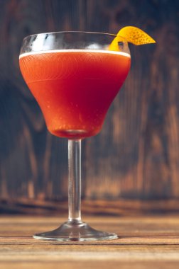 Bir bardak kan ve portakal kabuğuyla süslenmiş martini bardağında kum kokteyli.