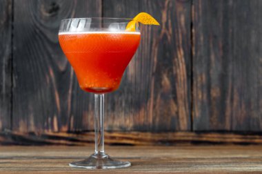 Bir bardak kan ve portakal kabuğuyla süslenmiş martini bardağında kum kokteyli.