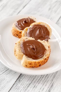 Beyaz tabakta çikolata ezmeli baget dilimleri.