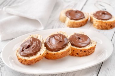 Beyaz tabakta çikolata ezmeli baget dilimleri.