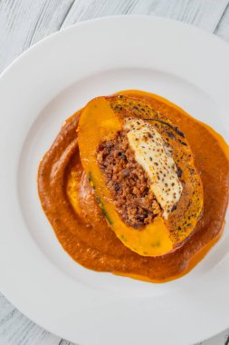 Savory portion of stuffed Hokkaido pumpkin topped with mozzarella, rich tomato sauce