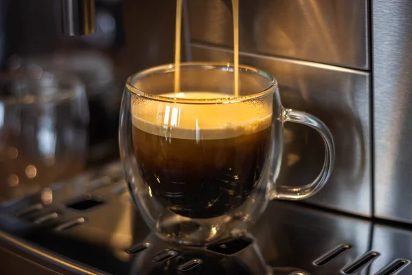 glass mugs with coffee in a coffee machine,cooking process, close-up