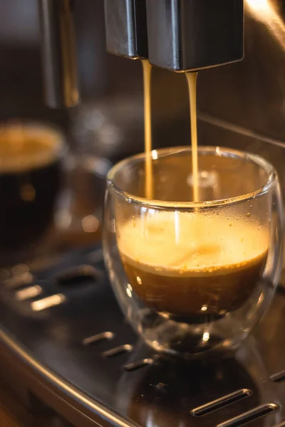 glass mugs with coffee in a coffee machine,cooking process, close-up