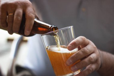 adam bir şişeden bir bardağa bira döker, çerçeve içinde eller, yakın çekim