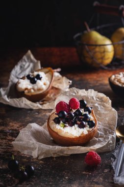 Bal, süzme peynir, ahududu ve kuş üzümü ile pişmiş armut. Taze ev yapımı tatlı. Düşük anahtarda yiyecek bileşimi. Yakın çekim, kopyalama alanı.