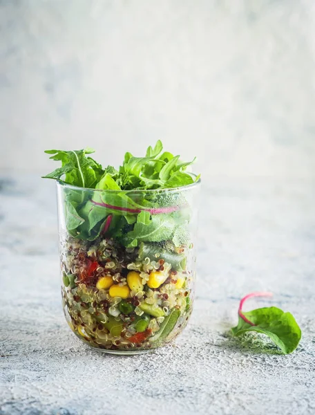 quinoa with vegetables in a glass cup with lettuce leaves, healthy eating concept, dietary vegetarian dish. Close-up, copy space, gray background.