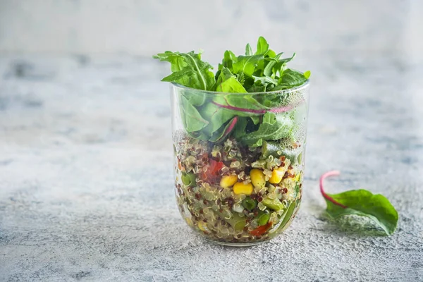 quinoa with vegetables in a glass cup with lettuce leaves, healthy eating concept, dietary vegetarian dish. Close-up, copy space, gray background.